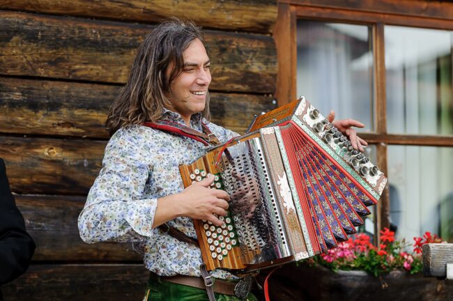 Hansi mit Steirischer vor Holzwand